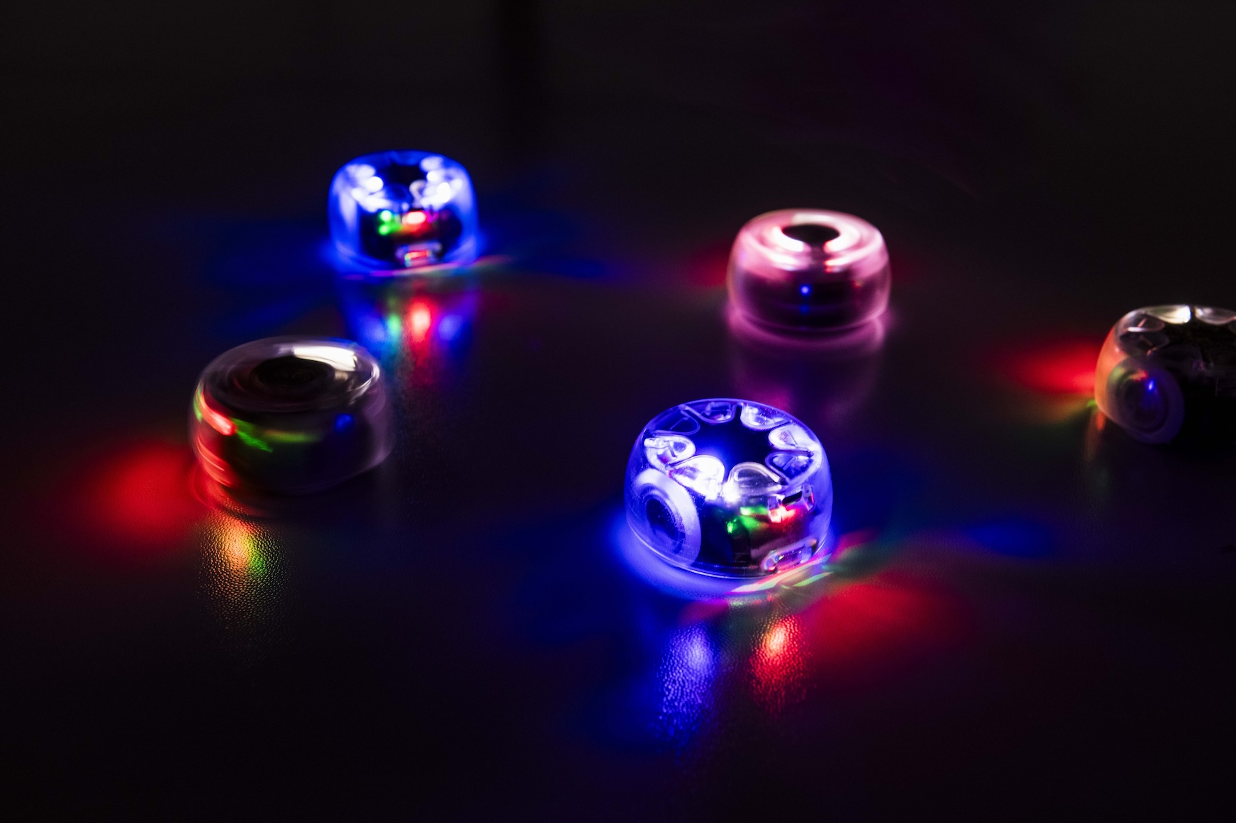An image of small glowing, circular robots in a dark space